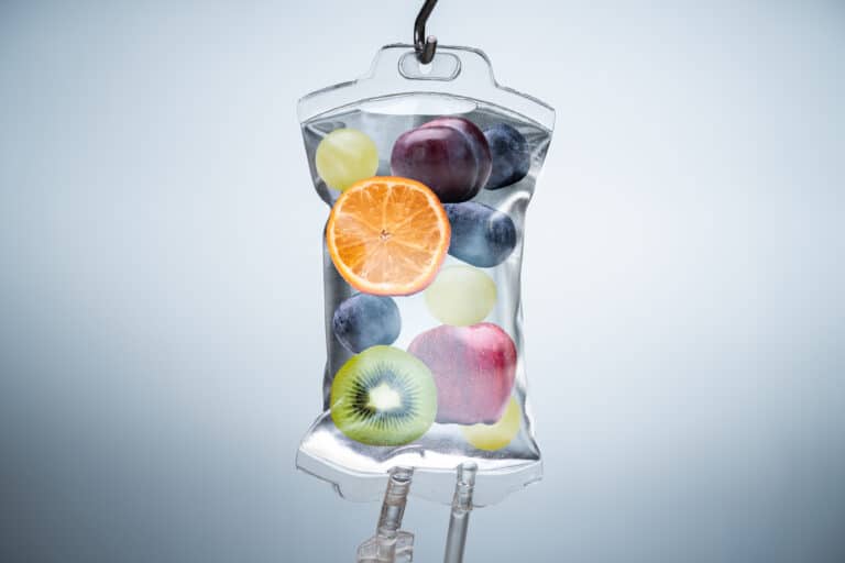 Close-up of different fruit slices inside an IV vitamins bag hanging in a hospital.