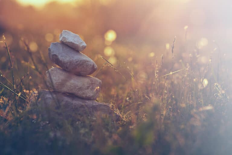Serene picture of rocks balanced on top of each other in a calming meadow.